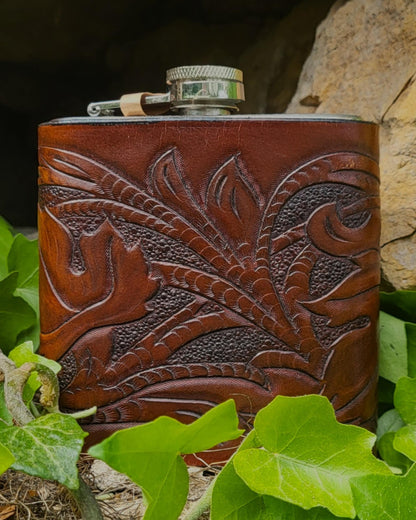 Edelstahl-Flachmann mit handgefertigtem Ledereinband, geziert von rankenden Weinblättern