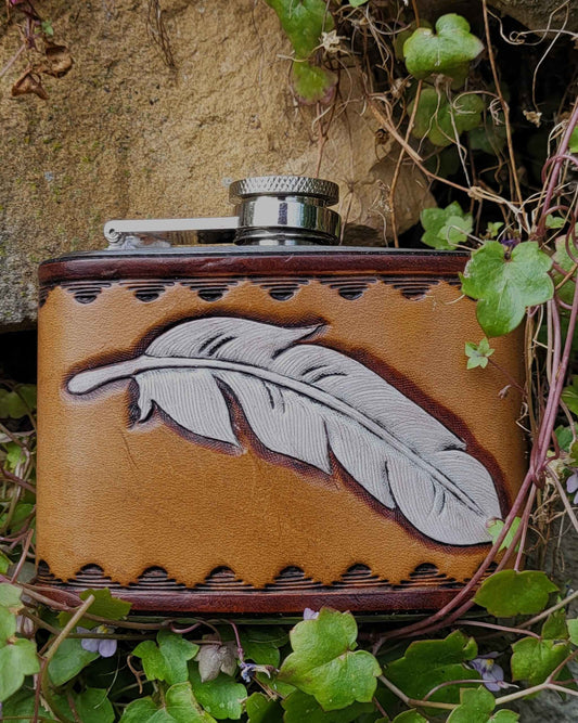 Edelstahl-Flachmann mit handgefertigtem Ledereinband, geziert von einer Feder